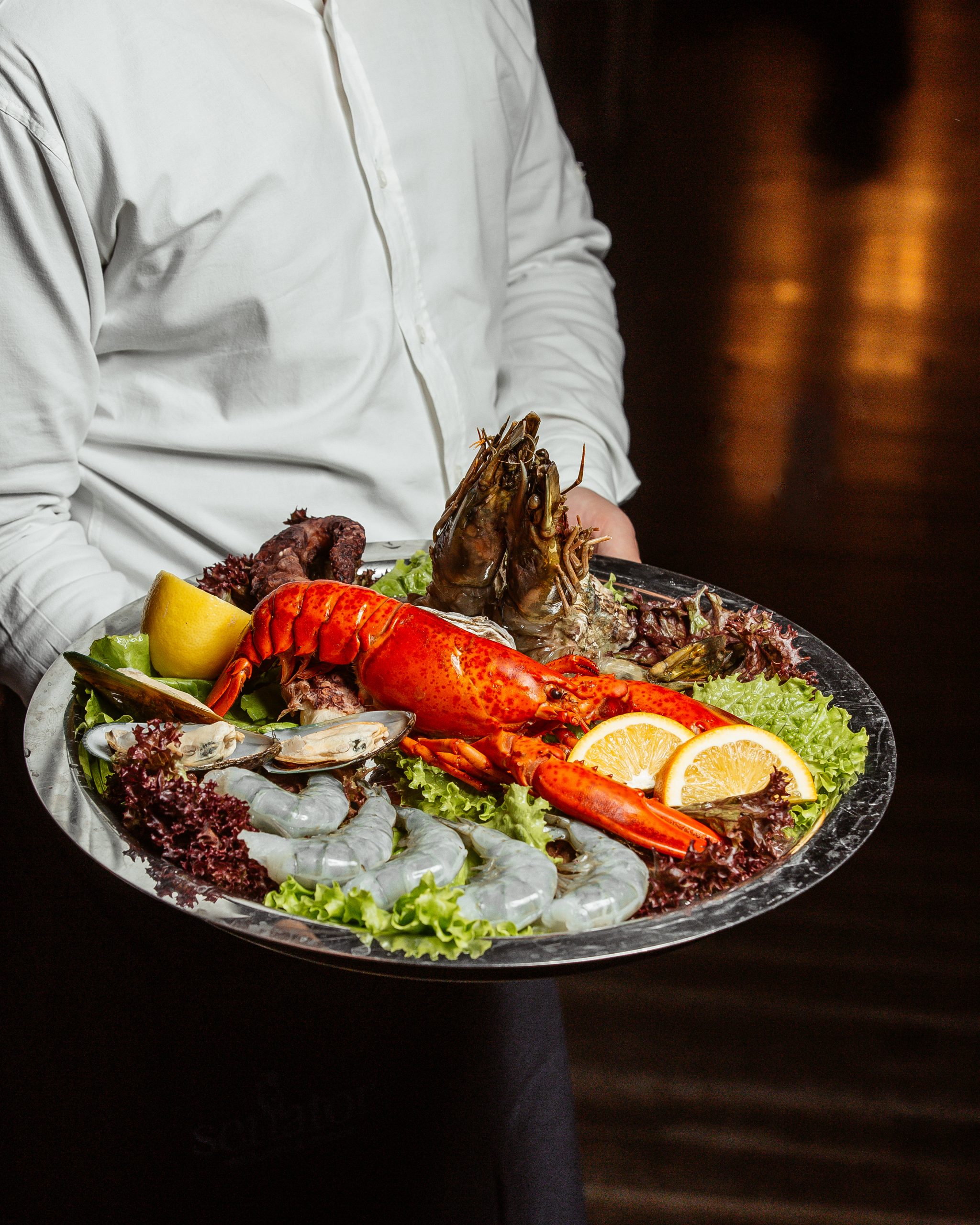 waiter holding seafood platter with lobster king prawns and mussels